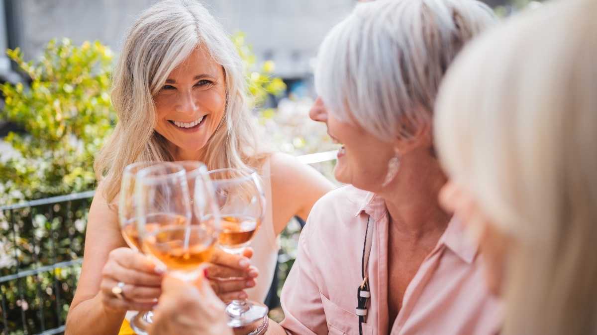 Três mulheres com taças de vinho, que afasta a osteoporose