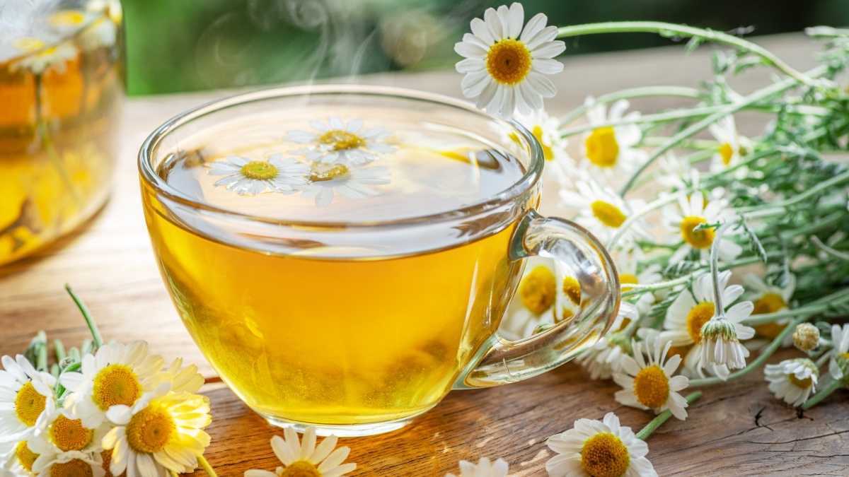 Uma caneca de chá de camomila ao lado de flores de camomila