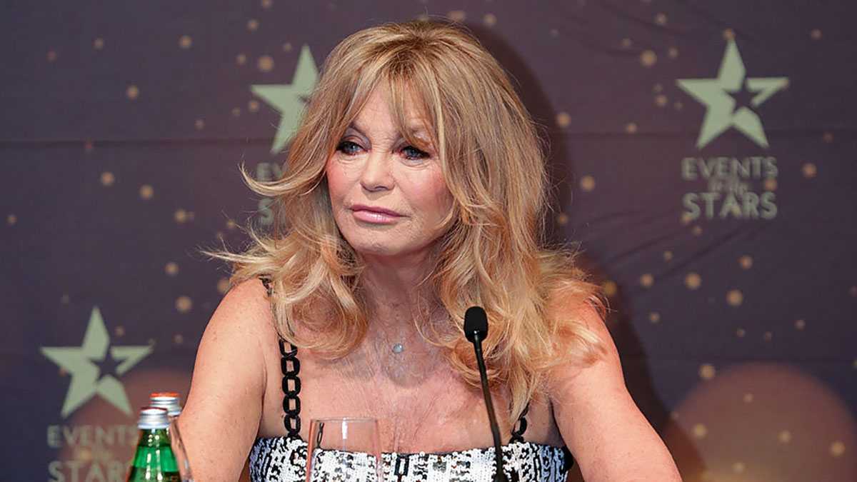 Herečka Goldie Hawn sedí na tlačovej konferencii s mikrofónom.