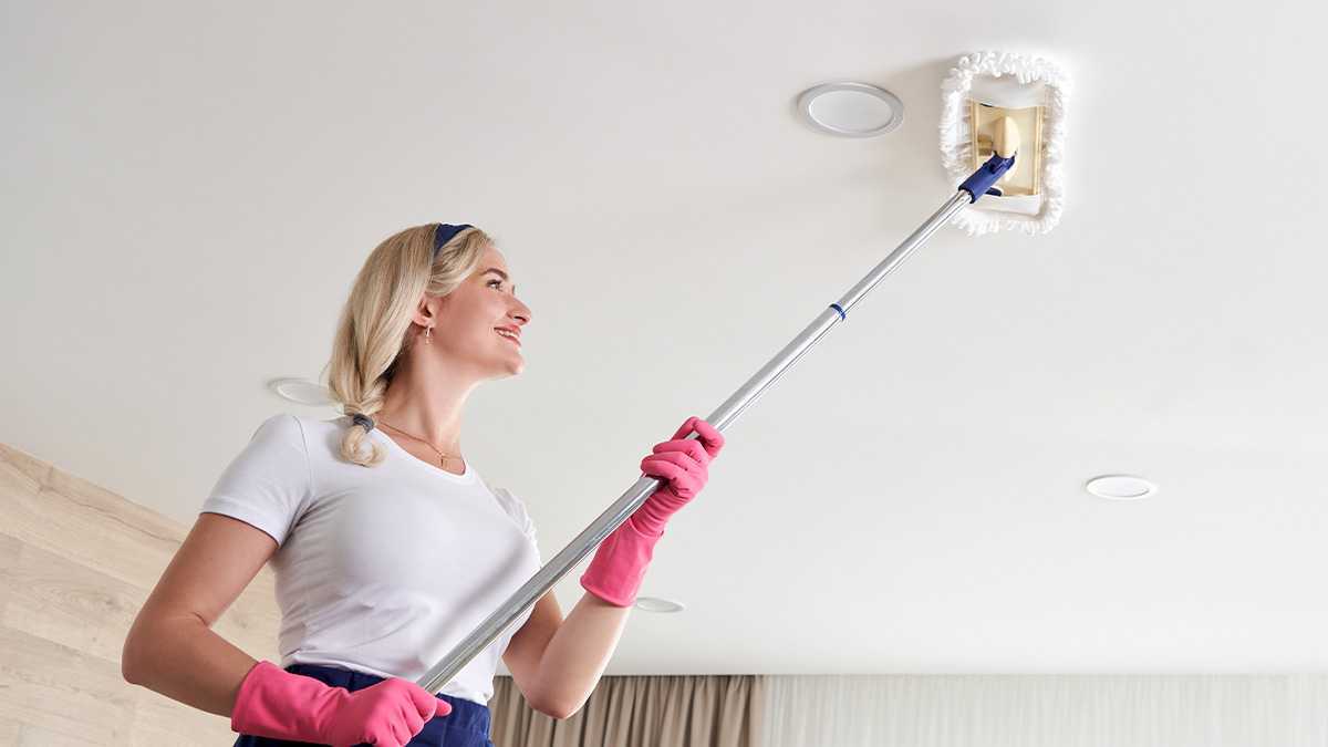 ผู้หญิงทำความสะอาดเชื้อราบนเพดานด้วยไม้ถูพื้น