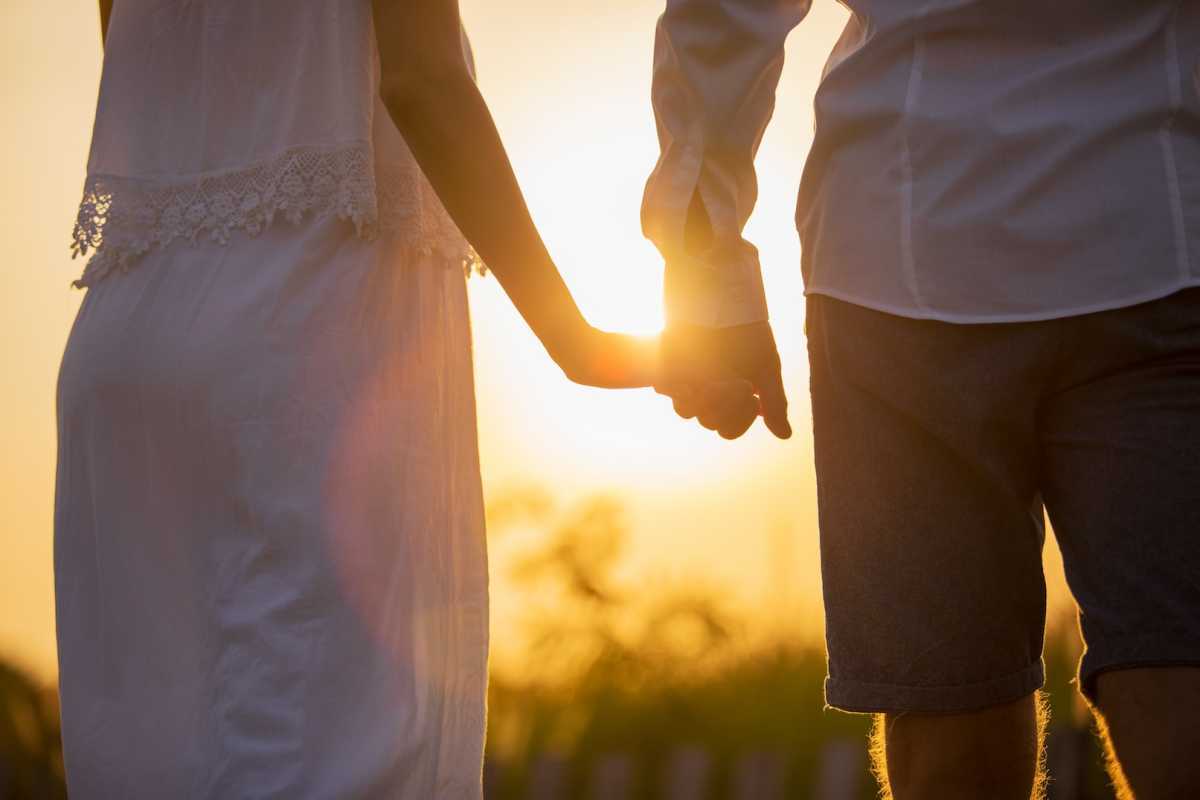 Pár sa drží za ruky pri západe slnka (kompatibilita Vodnára a Strelca)