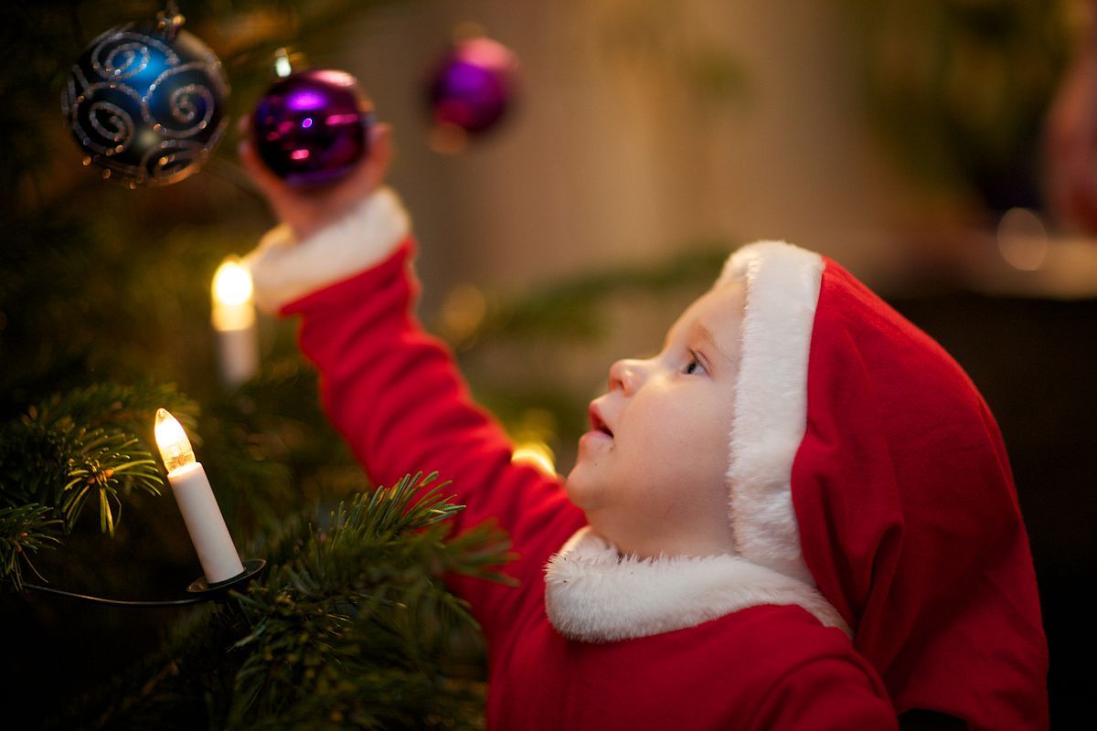 criança decorando árvore de natal